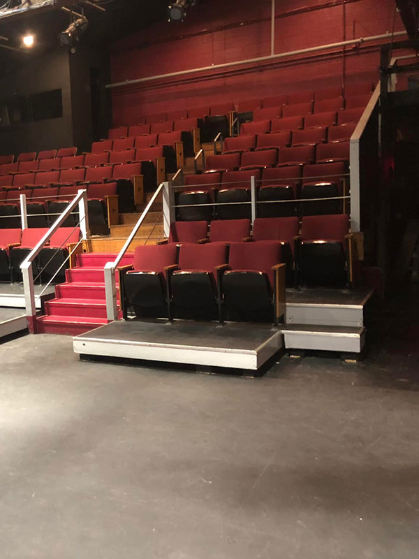 A photo of an empty theatre with red seats.