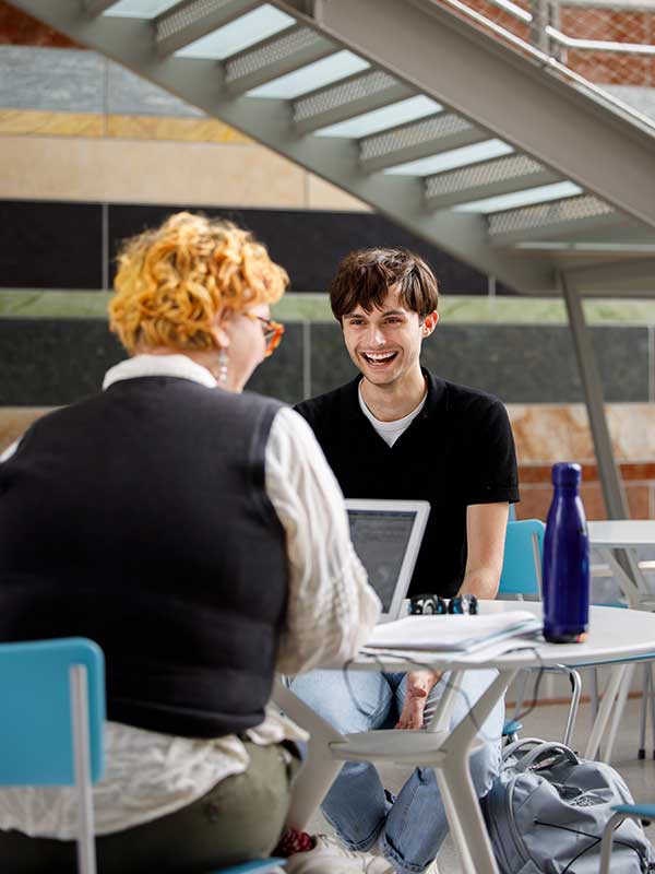 Two students chat a table in the SGIS building.