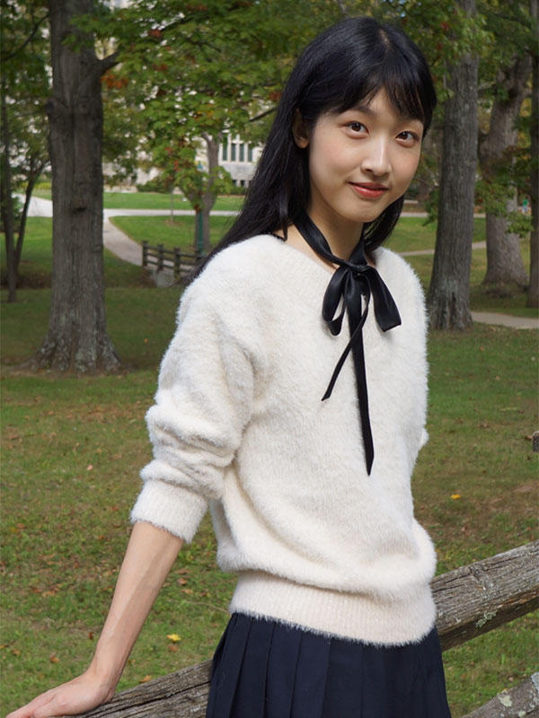 A photo of Jingyi Guo, who wears a white sweater and poses in Dunn Meadow.