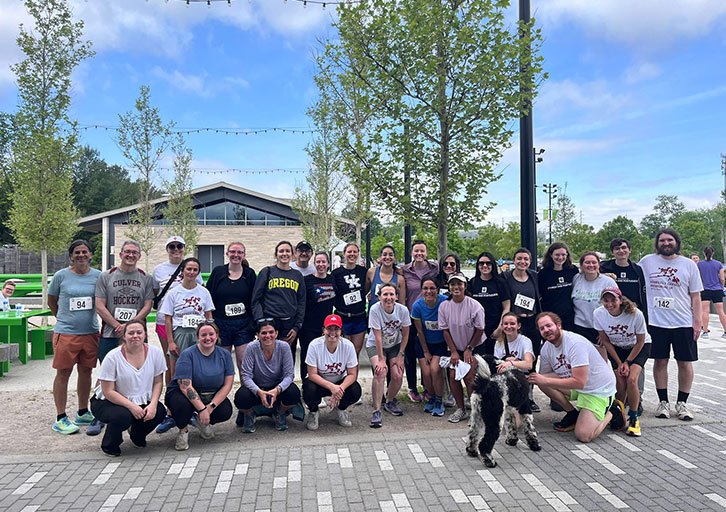 A group of people pose together at a park outside.