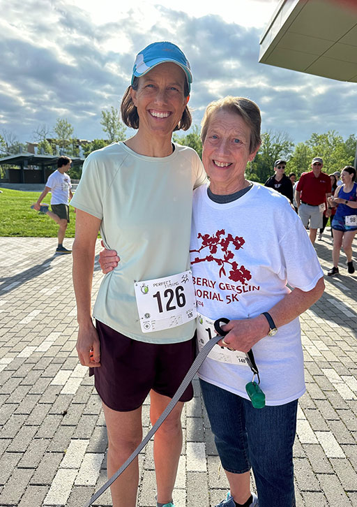 Two people pose together at a 5K in a park.