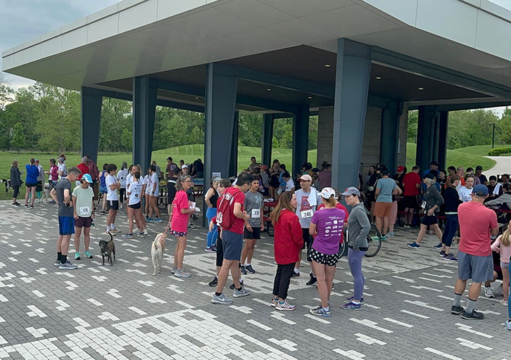 A large group of people talk at a park.