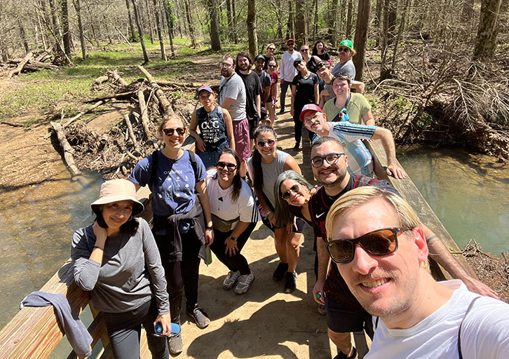 A group of people pose together on a wooden bridge.