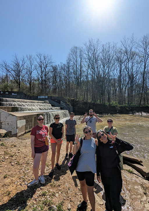 People pose on a sunny day near a dam.