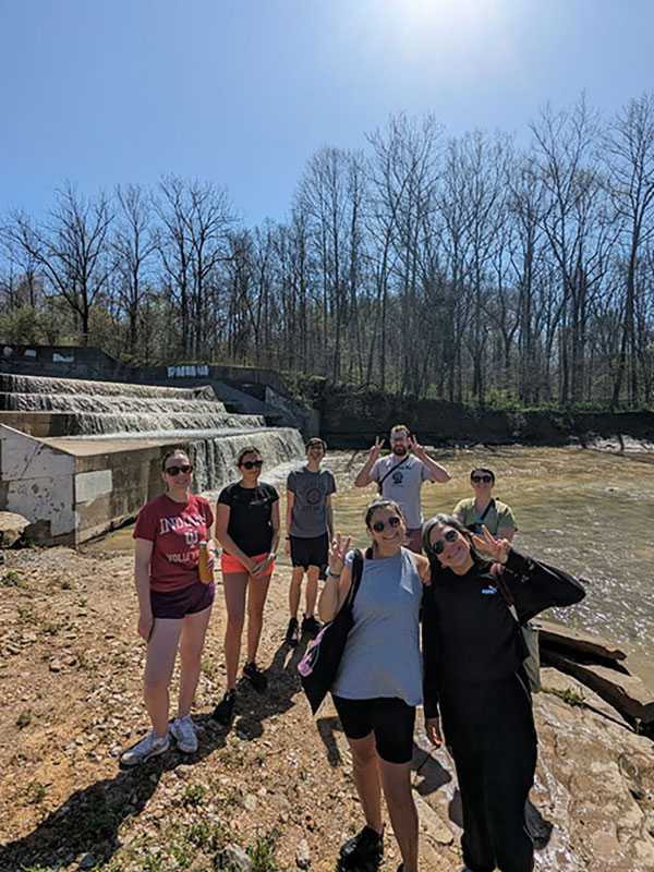 Students pose outside near a forest.