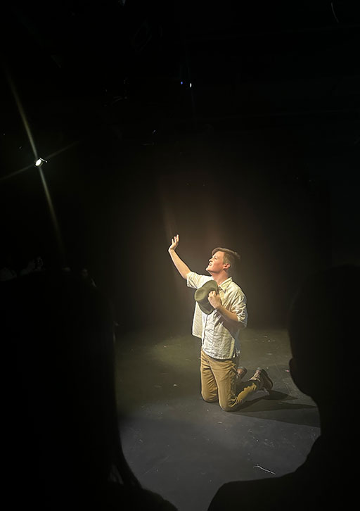 A person kneels on a stage.