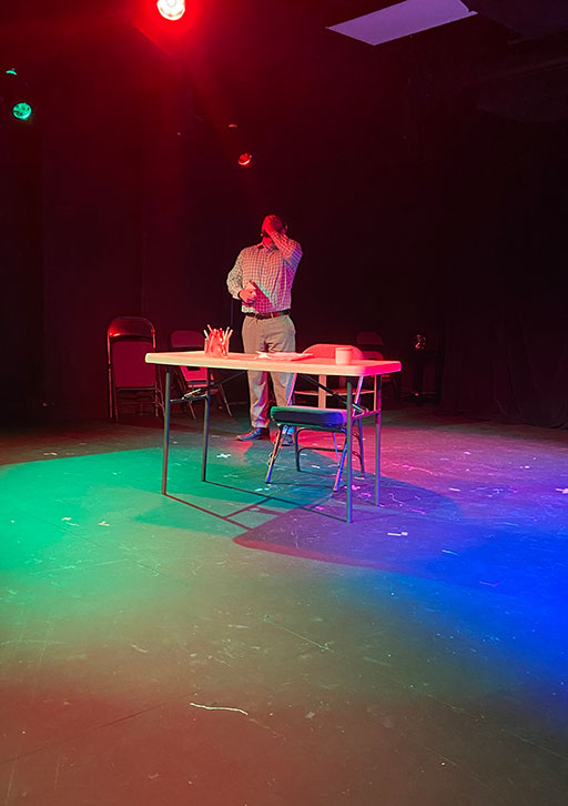 A person performs on a stage, acting.