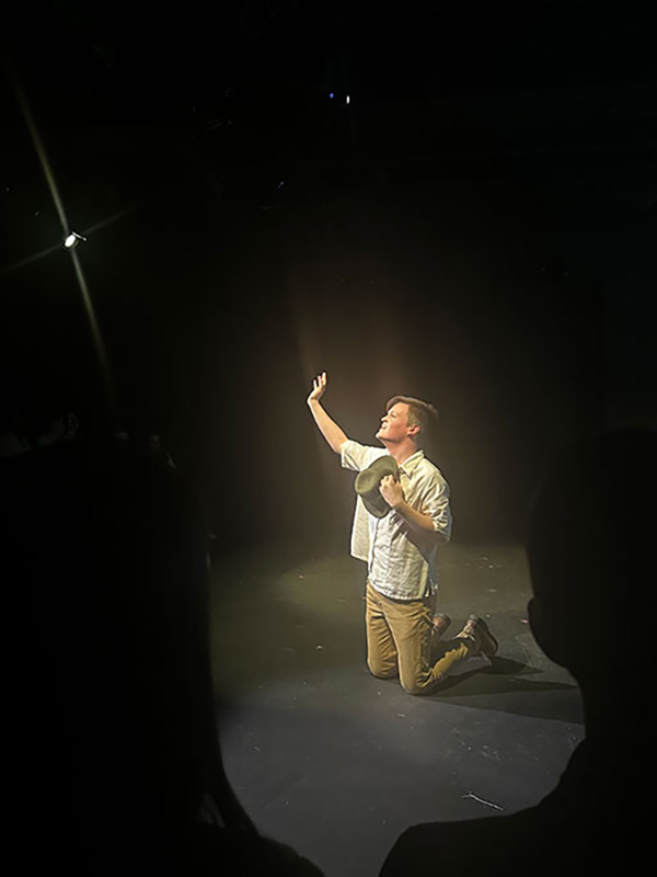 A student performs on a dark stage.