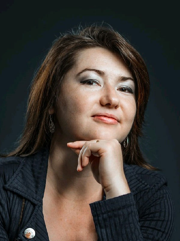 A headshot of Valentine Filimonova, who wears a black sweater and poses with her hand on her chin.